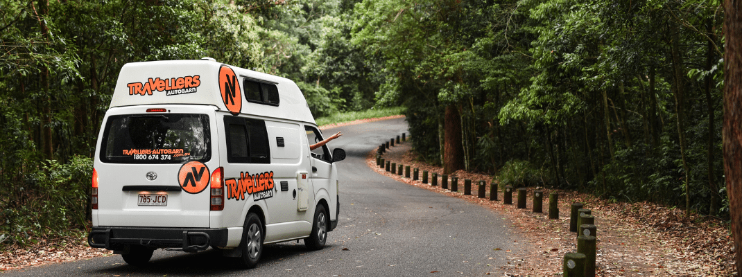 Campervan on road through rainforest in Queensland, Australia