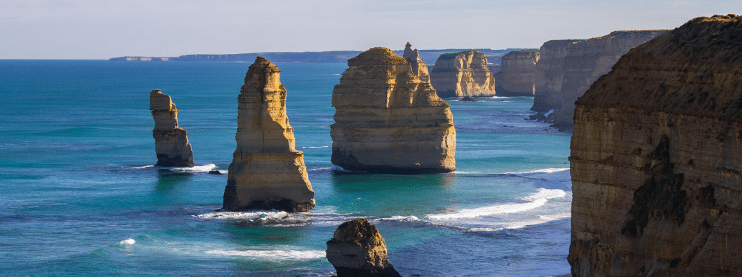 The Twelve Apostles (limestone stacks) stand in the beautiful green water of the Southern Ocean on a sunny day near the Great Ocean Road in Victoria, Australia.
