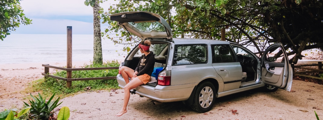 A woman relaxing beachside with an automatic transmission ford station wagon